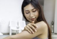 Young Asian woman with healthy skin applying sunscreen UV protect to shoulder.