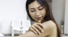 Young Asian woman with healthy skin applying sunscreen UV protect to shoulder.