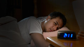 Depressed man suffering from insomnia lying in bed
